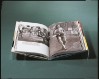 Open book displayed on a clear acrylic stand in front of a dark green background