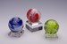 Three variously-colored Glass Marbles on a Square Dimple Base