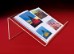 Open book displayed on a clear acrylic stand in front of a red background